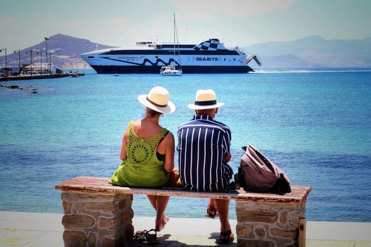 Un couple assis face à la mer en Grèce, moment de calme et de vacances pour se reconnecter loin du travail.
