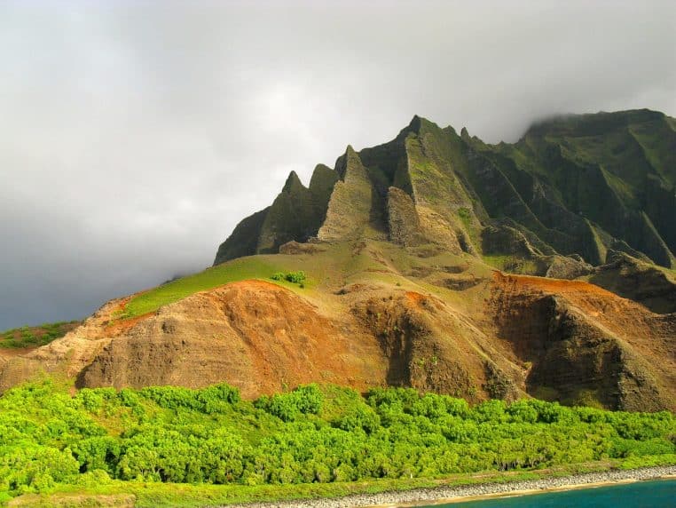 Falaises verdoyantes plongeant dans l’océan au large de Kauai, montrant la diversité des paysages de l’archipel hawaïen.