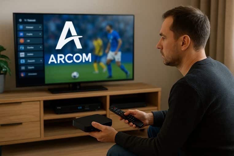 Homme tenant une box IPTV et une télécommande dans un salon, face à un téléviseur montrant un match de foot et le logo Arcom.