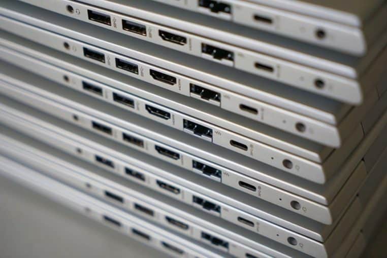 Empilement de plusieurs ordinateurs portables montrant la tranche latérale, avec leurs ports USB, HDMI et prises audio alignés.