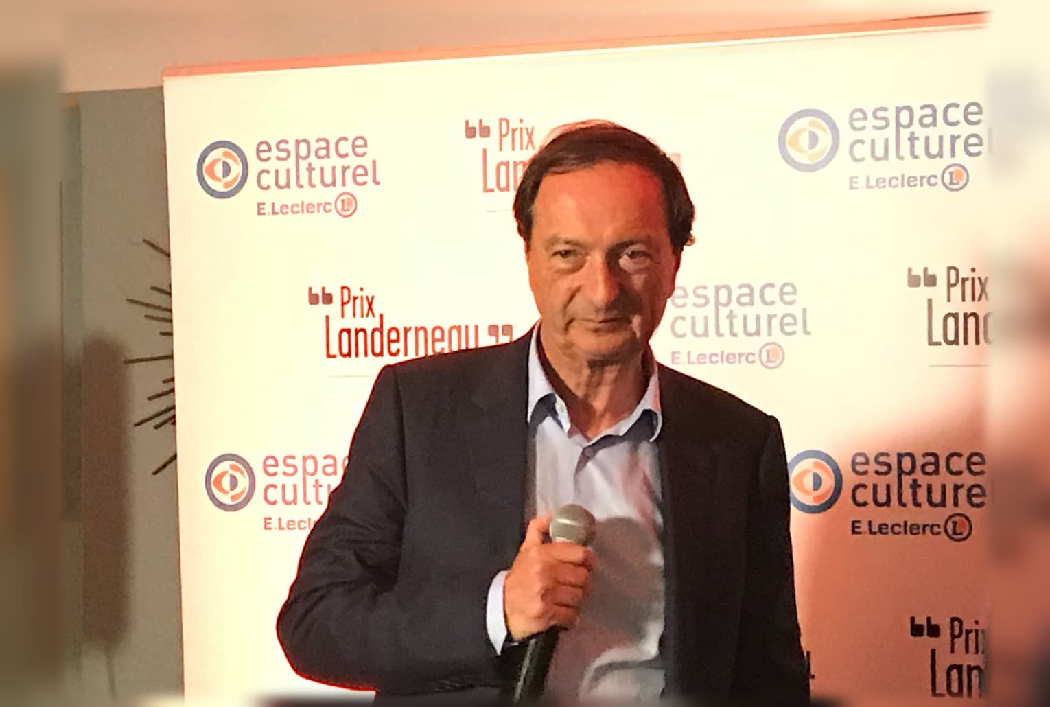 Michel-Édouard Leclerc en costume, micro en main, lors d’un événement Prix Landerneau E.Leclerc.