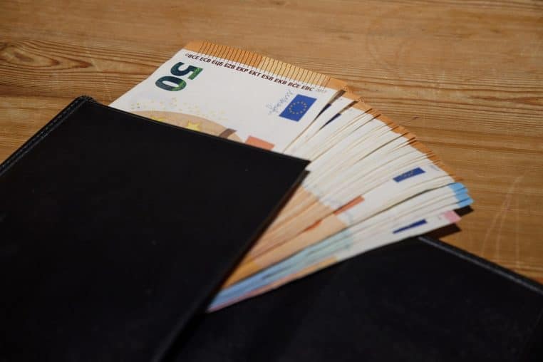 Portefeuille ouvert rempli de billets en euros disposés sur une table, illustrant une importante somme d’argent immédiatement disponible.
