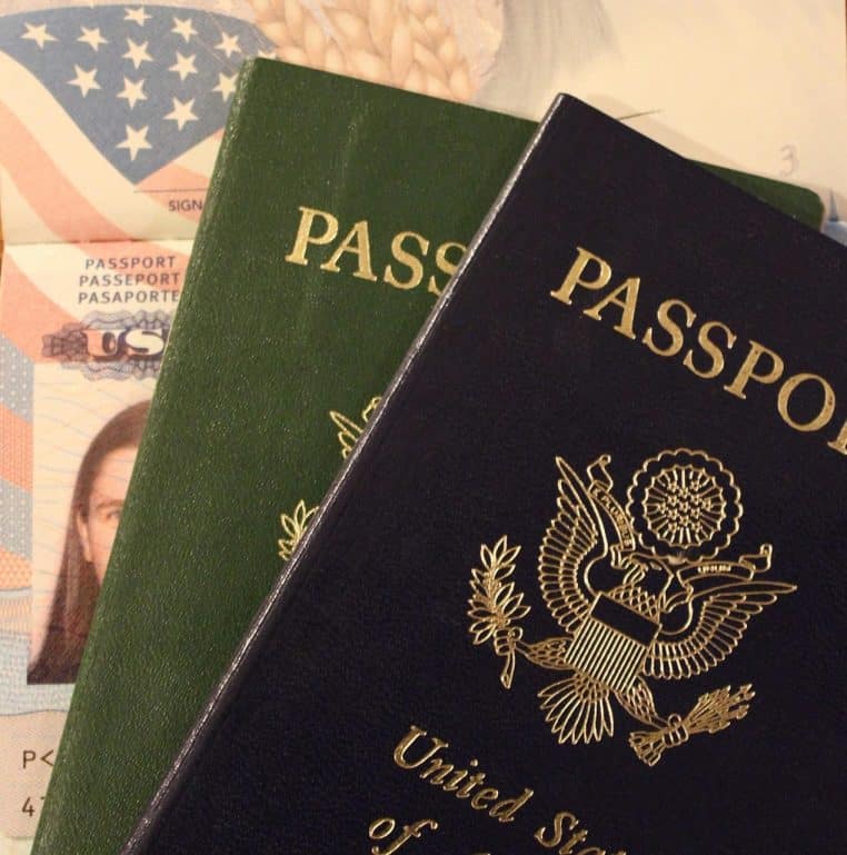 Passeport américain posé sur d’autres documents de voyage, symbole des formalités d’entrée imposées aux touristes se rendant aux États-Unis.