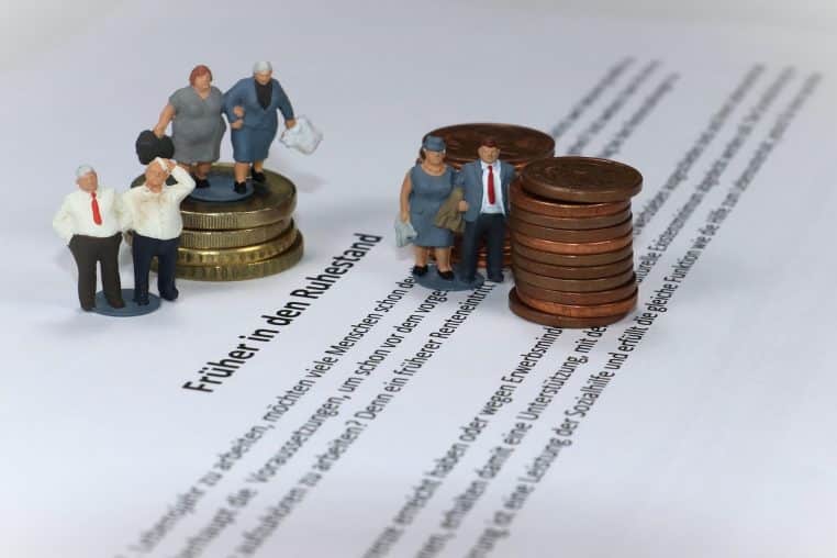 Figurines miniatures de seniors assis sur des pièces de monnaie symbolisant une pension de retraite et son niveau de revenu.