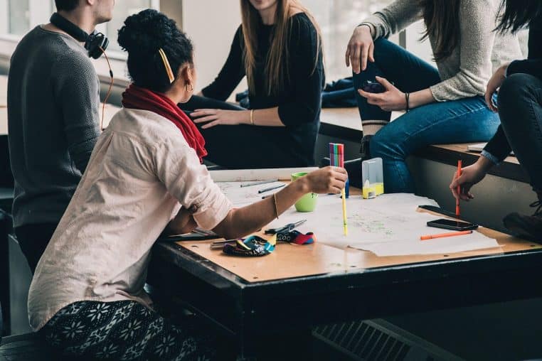Étudiantes assises autour d’une table en train de discuter, concentrées et souriantes, illustrant une conversation détendue et collaborative.