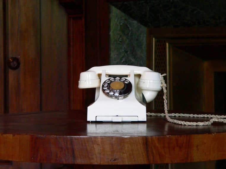 Téléphone de bureau posé sur une table de travail, entouré de matériel informatique, renvoyant à l’ambiance des plateaux d’appels.