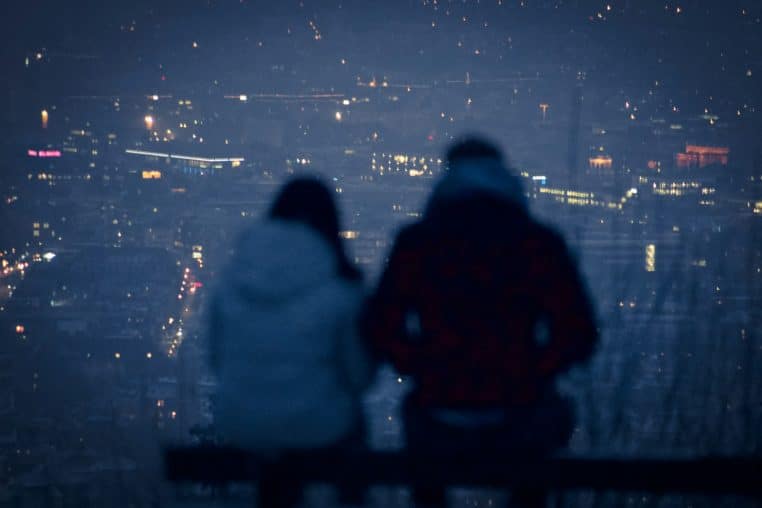 man and woman sitting on bench during night time