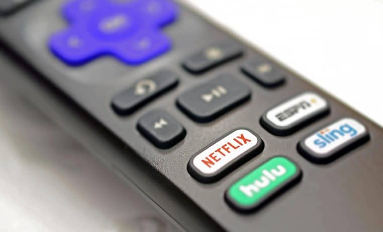 Gros plan d’une télécommande posée sur une table avec un bouton Netflix rouge bien visible, symbolisant l’accès simplifié aux plateformes de streaming vidéo.
