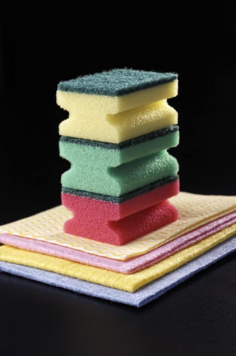 Gros plan sur une pile d’éponges colorées posées sur des chiffons de ménage, prête à servir pour le nettoyage de la salle de bain et des toilettes.