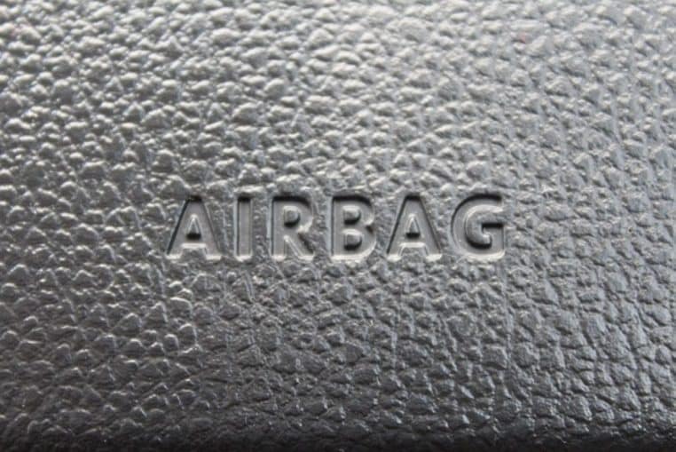Gros plan sur une texture de tableau de bord en plastique noir avec l’inscription airbag embossée au centre de l’image.
