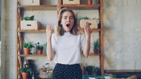 Surprised young woman with hands raised in air.