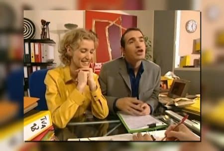Alexandra Lamy et Jean Dujardin dans « Un gars, une fille », assis à un bureau, scène intérieure.