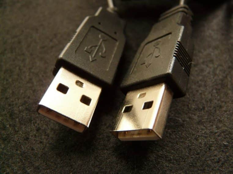 Gros plan sur deux connecteurs USB de type A posés côte à côte sur un tissu sombre, montrant clairement la forme standardisée des prises métalliques.