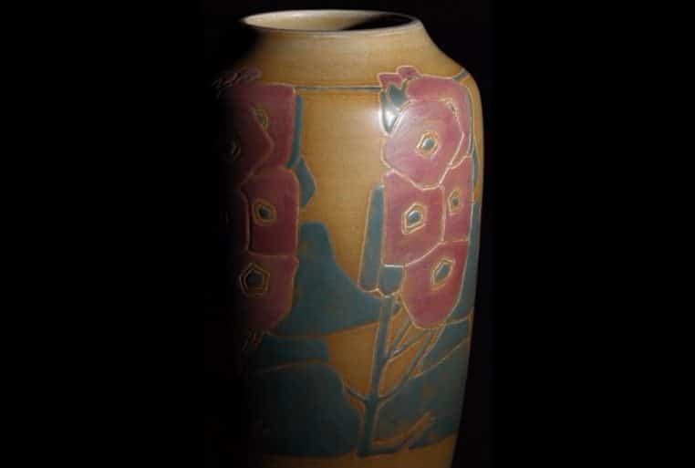 Vase en céramique Overbeck décor floral rouge et bleu, photographié sur fond noir, en lumière rasante.