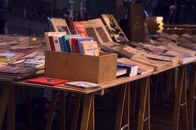 Stand de brocante rempli de boîtes et de livres anciens empilés, représentant des trésors oubliés à transformer en argent.