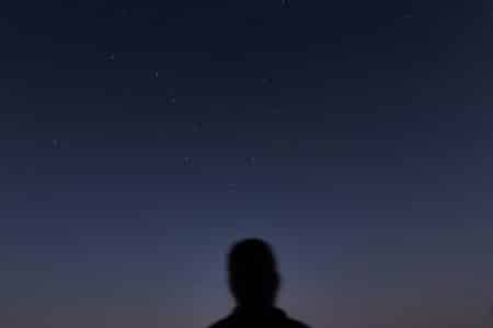 man in black jacket standing under blue sky during night time