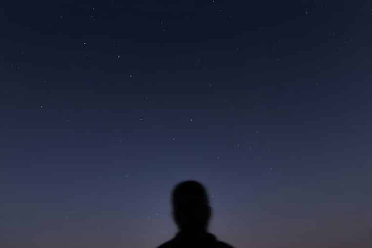 man in black jacket standing under blue sky during night time
