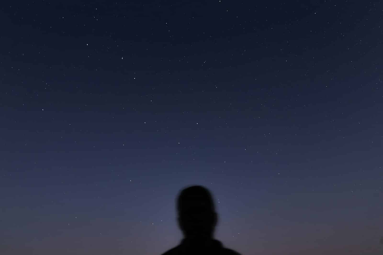 man in black jacket standing under blue sky during night time