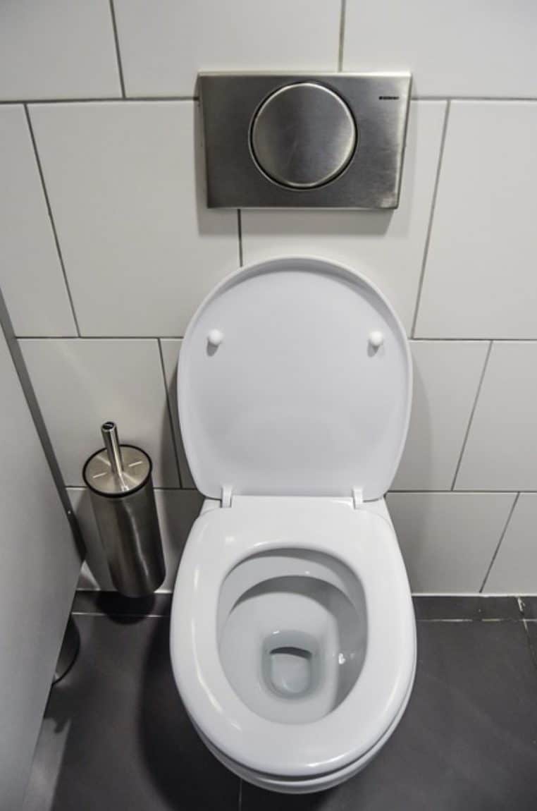 Cuvette de toilettes en céramique blanche ouverte dans une salle de bain moderne, prête à être nettoyée pour retirer le tartre.