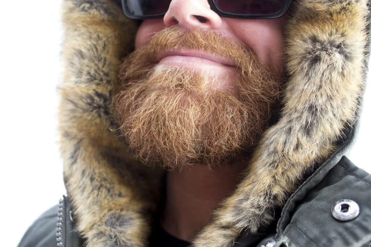 Rangée de vestes d’hiver épaisses aux couleurs neutres suspendues sur des cintres dans une pièce lumineuse