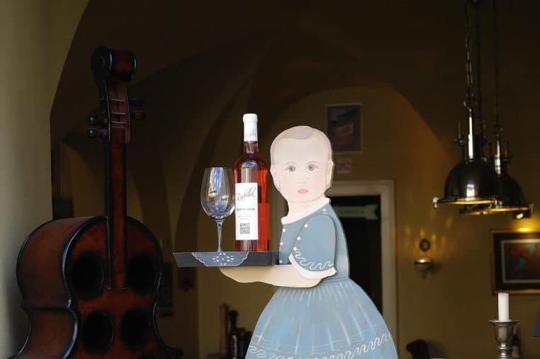 Jeune femme assise tenant un verre de vin rouge à la main dans un décor tamisé, illustrant une consommation d’alcool occasionnelle.