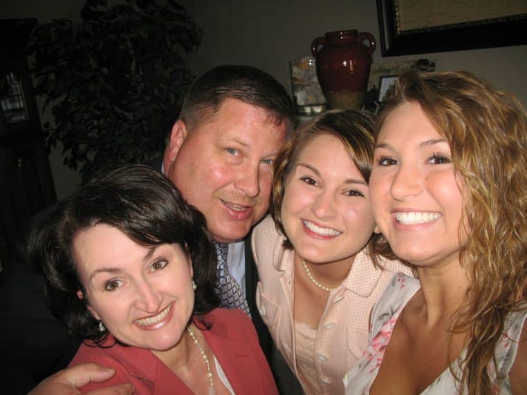 Portrait de famille souriante en intérieur, quatre personnes rapprochées devant l’objectif lors d’une photo souvenir.