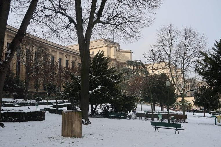 Vue du Trocadéro à Paris recouvert de neige fraîche, passants et arbres d’hiver sous un ciel gris