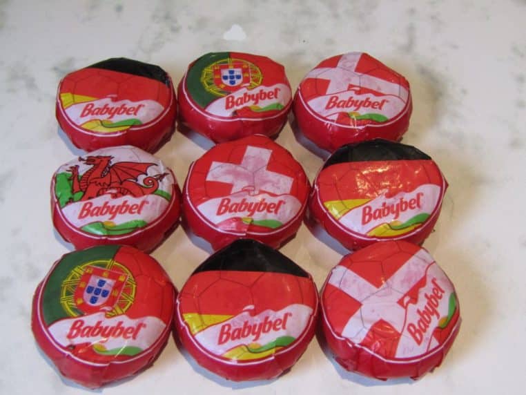 Promotions de Mini Babybel en cire rouge alignées sur un plan de travail, photo prise en cuisine.