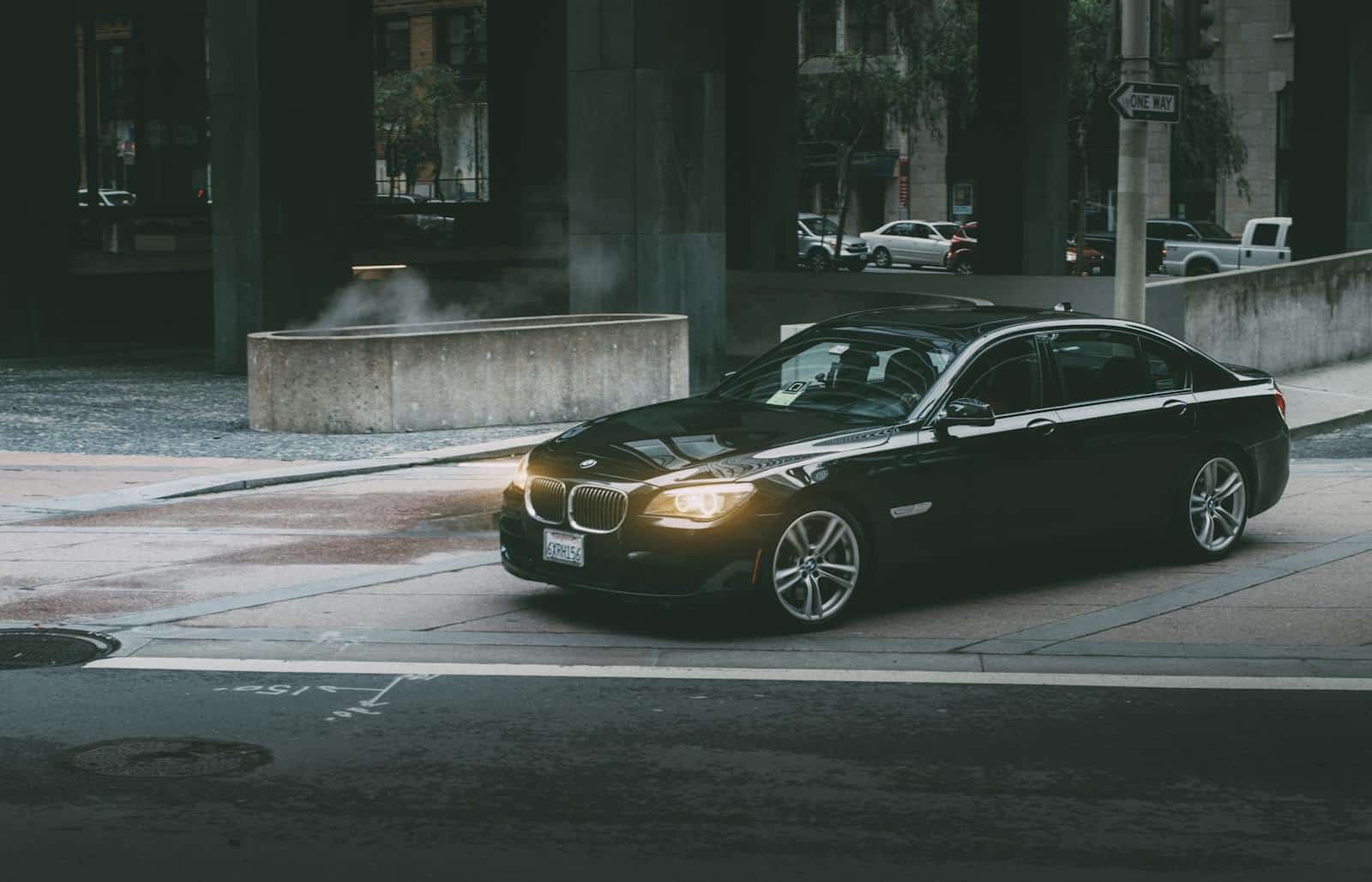A luxury black car navigating city streets at twilight, showcasing modern city life and design.