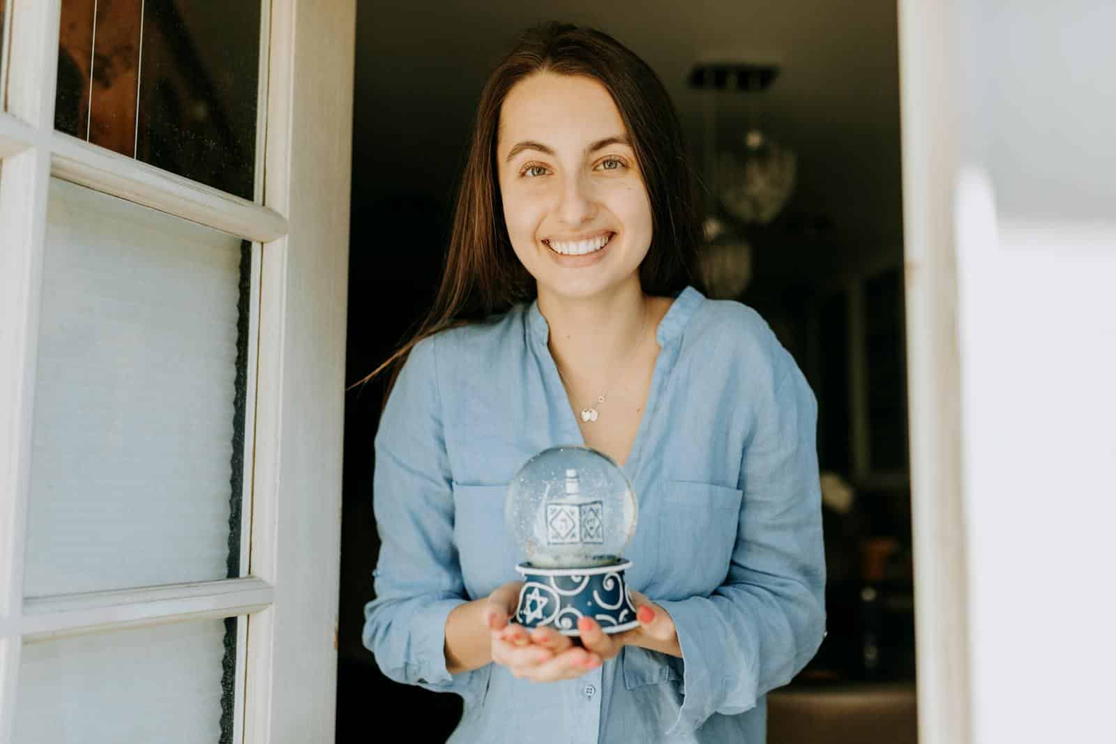 A happy woman poses with a decorative Hanukkah snow globe, capturing the festive spirit.