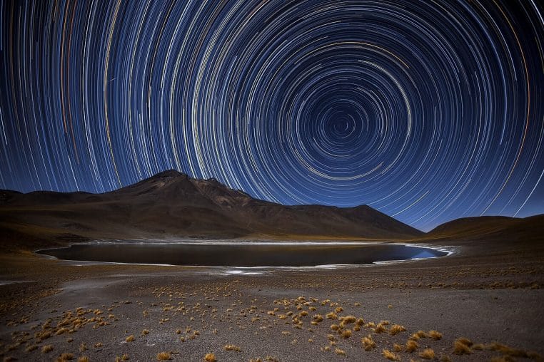 Traînées d’étoiles en rotation dans un ciel nocturne très net, photo longue pose montrant le mouvement des astres.