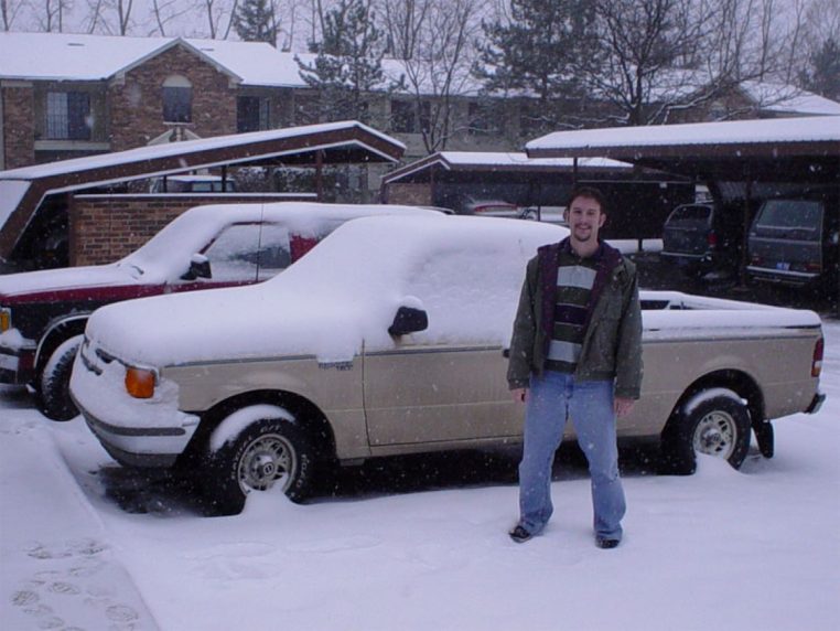 Véhicule utilitaire enneigé sur route, conditions difficiles.