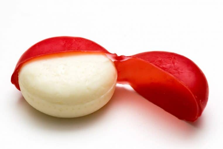 Mini Babybel ouvert montrant le fromage, coque de cire rouge pliée sur le côté, gros plan lumineux.