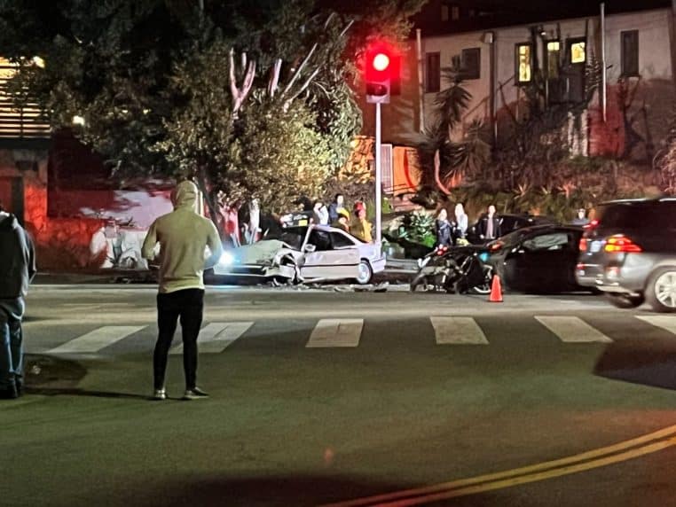 Accident de voiture de nuit à un carrefour, gyrophares et véhicules accidentés sous un feu rouge.