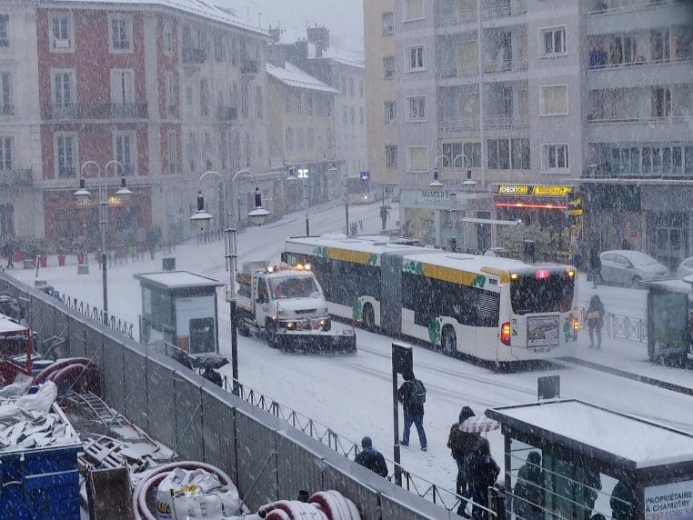 Un chasse-neige croise un bus urbain à Chambéry lors d’un matin neigeux