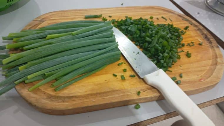 Oignons nouveaux émincés sur une planche, couteau au centre