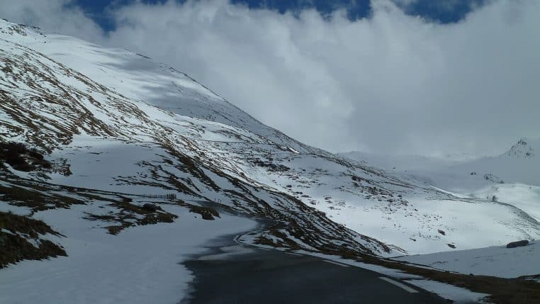 Panneau routier du col du Mont-Cenis partiellement enseveli, entouré de neige épaisse.