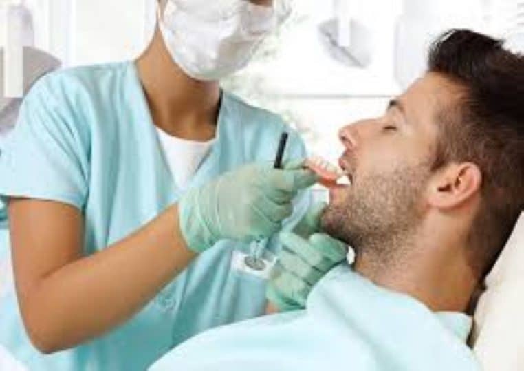 Un professionnel ajuste une prothèse dentaire directement dans la bouche d’un patient.