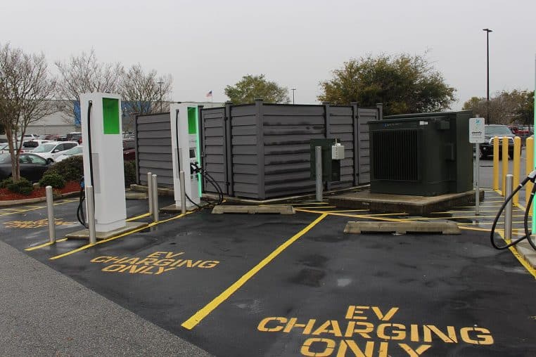 Aire de recharge avec plusieurs bornes pour véhicules électriques, marquage au sol et emplacement dédié, vue large.
