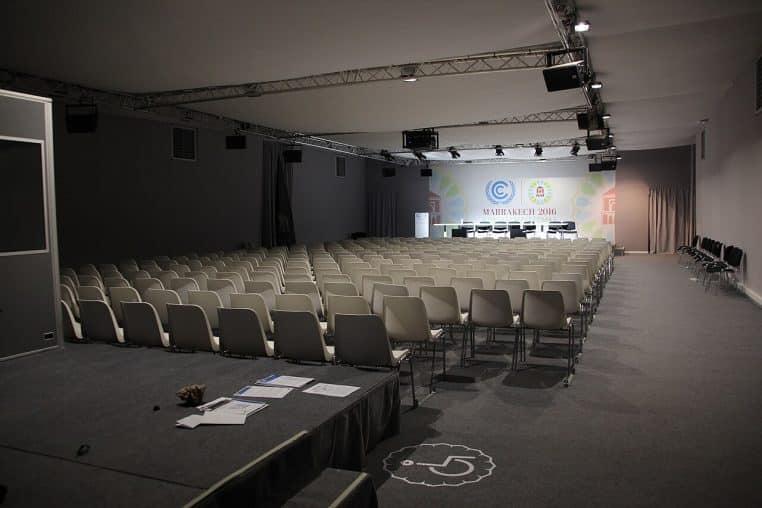 Salle de réunion vide avec rangées de chaises et tables, vue en perspective