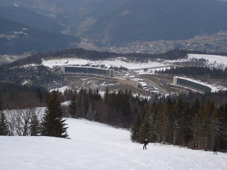 Skieurs sur une piste verte à Villard-Corrençon (Vercors), neige damée, sapins et immeubles des Glovettes.