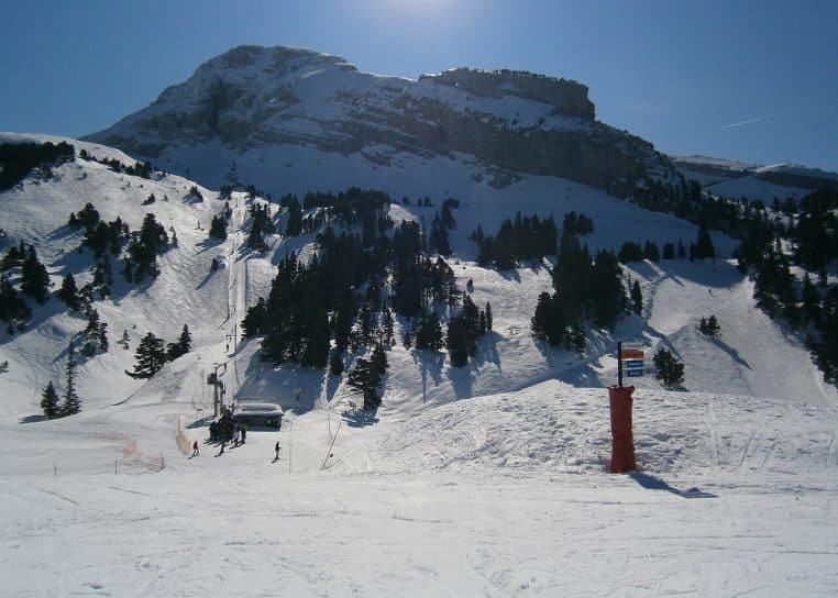 Départ du téléski Ourson à Villard-Corrençon, neige au sol, forêt du Vercors et ciel clair en arrière-plan.