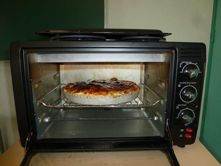Galette des rois en cuisson dans un four électrique, frangipane dorée et feuilletage en formation, gros plan.