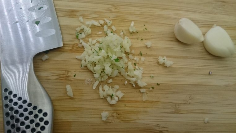 Ail fraîchement haché sur une planche en bois, en gros plan