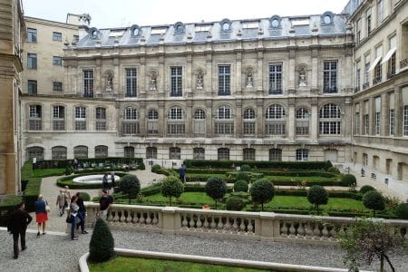 Jardin de l’Hôtel de Toulouse (siège de la Banque de France) à Paris, avec parterres symétriques, allées et façade classique en pierre, vue en format paysage.
