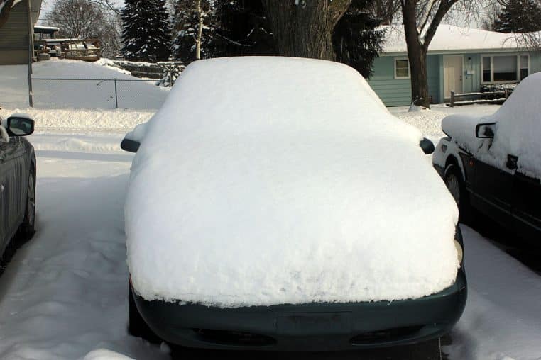 Voiture entièrement recouverte de neige, stationnée dehors au petit matin après une nuit de grand froid.