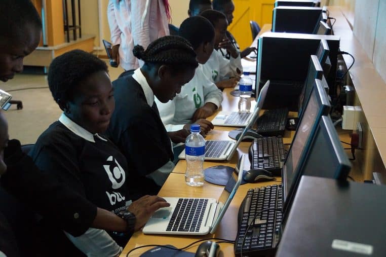 Adolescentes devant des ordinateurs en salle de classe, concentrées sur un atelier numérique, ambiance scolaire et studieuse.