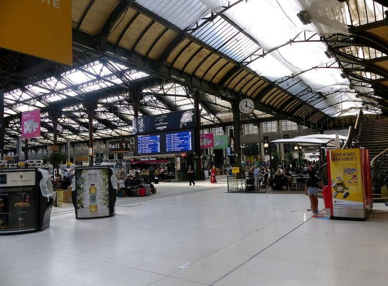 Grand hall intérieur de la gare de Lyon à Paris, avec voyageurs et panneaux d’affichage.