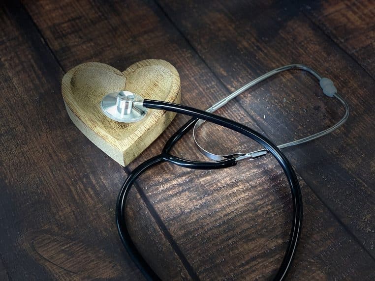 Stéthoscope posé à côté d’un cœur en bois sur une table