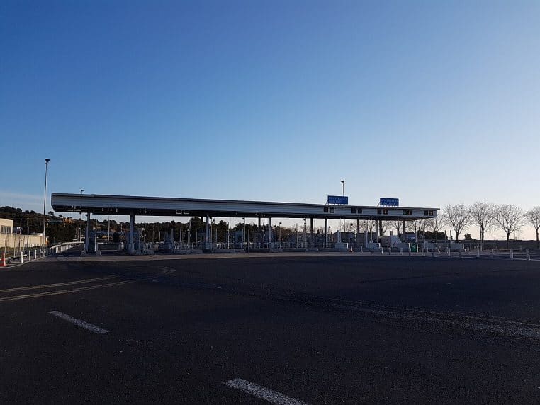 Péage de l’autoroute A9 au Boulou, grand auvent et voies désertes sous un ciel bleu, format paysage.